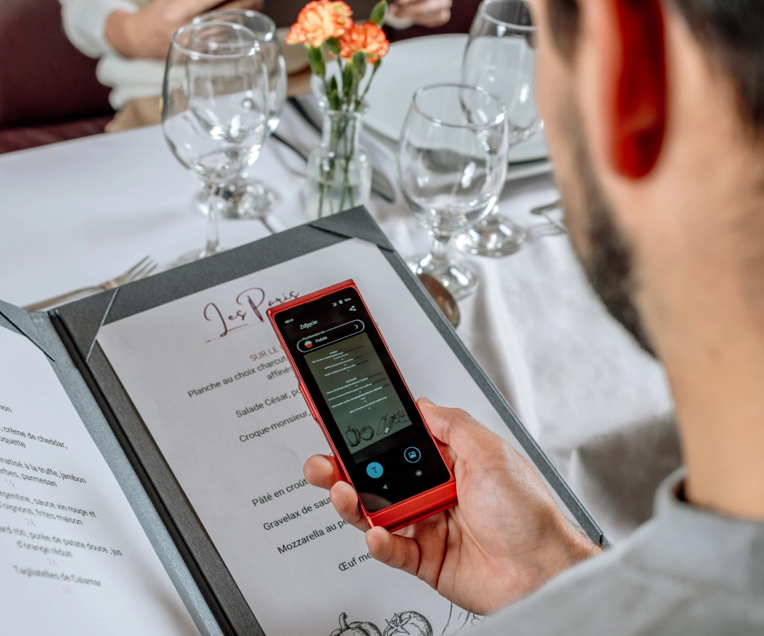 mężczyzna w eleganckiej restauracji tłumaczący menu za pomocą fototłumacza w elektronicznym translatorze