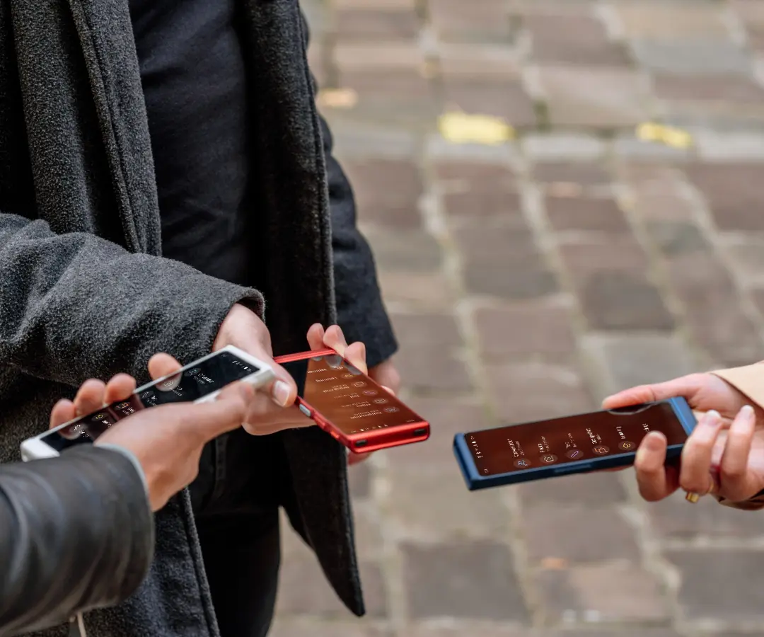 Trzech przyjaciół szczęśliwie trzymających swoich tłumaczy, zaangażowanych w rozmowę i dzielących wspólne chwile. 