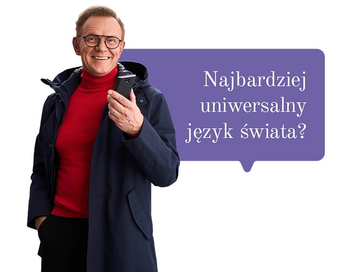 Uśmiechnięty Cezary Pazura w czerwonym swetrze, owinięty lampkami, trzyma w ręce pudełko Vasco Translatora. W tle dymek z tekstem: Najbardziej uniwersalny język świata?