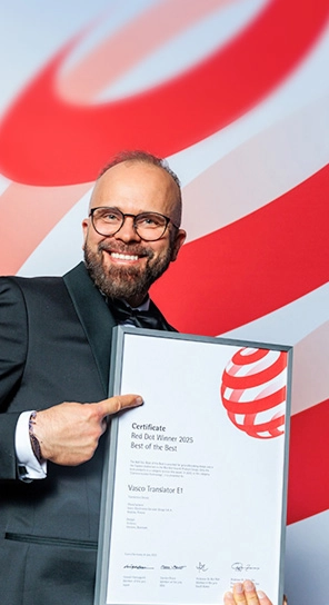 Prezes firmy Vasco Electronics trzyma w ręku nagrodę Red Dot i prezentuje nagrodzone urządzenia.
