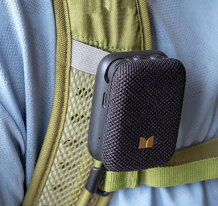 Czarny mini głośnik Bluetooth przypięty do oliwkowo-zielonego paska plecaka